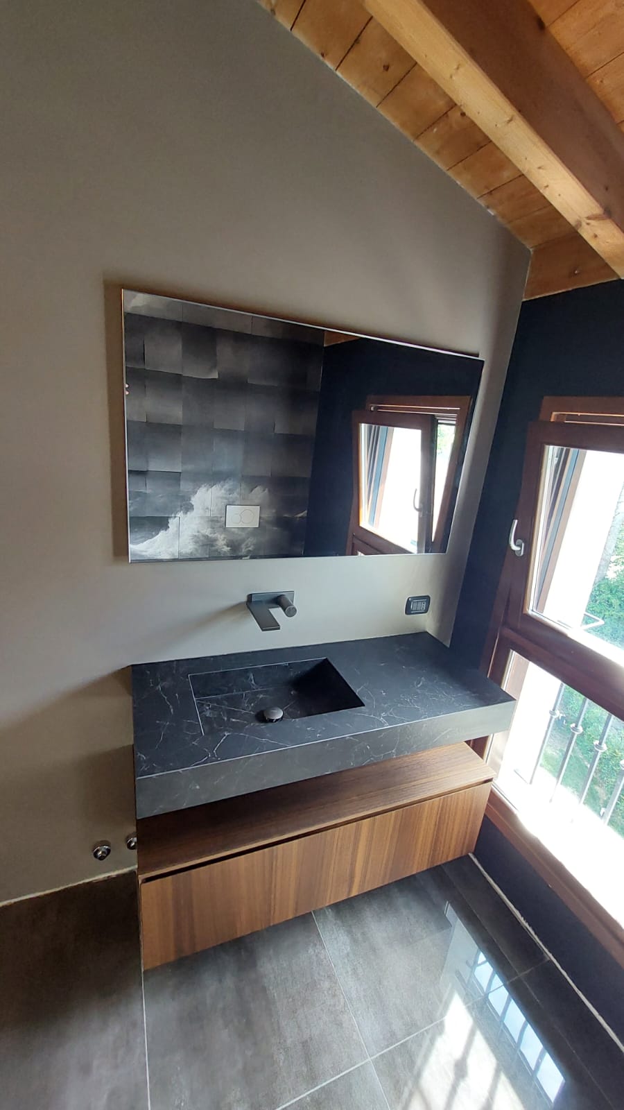 un bagno moderno con piastrelle grigie quadrate, sanitari sospesi e un mobile in legno